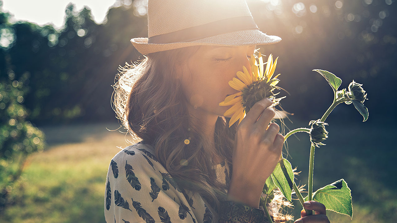 Nachhaltiges ETF-Portfolio Frau mit Hut riecht an einer Sonnenblume