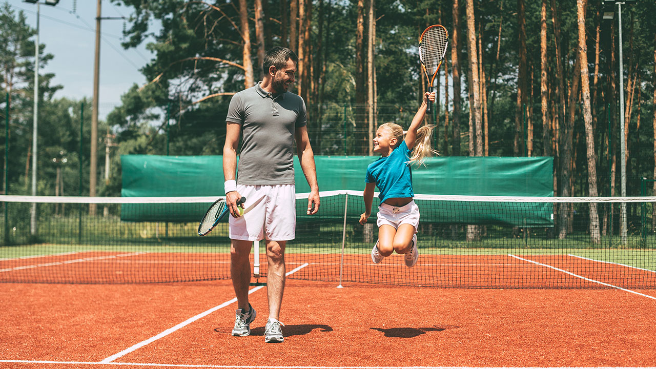 Gemanagte ETF-Portfolios Vater und Tochter mit Tennisschlägern auf Tennisplatz