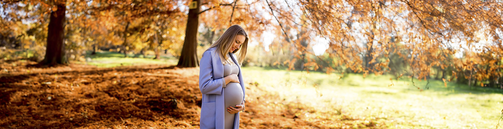Finanziell Vorsorgen für Kinder Schwangere Frau blickt lächelnd auf Ihren Babybauch